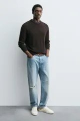 Zapatilla deportiva de corte bajo, color blanco con detalle en tono beige en el talón. Presenta cierre con cordones y suela de goma con volumen.