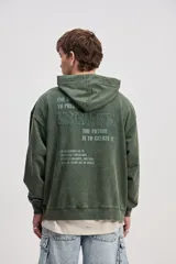 Canguro de algodón con efecto lavado de corte oversize, capucha con cordones ajustables, bolsillo canguro delantero y estampa frontal con texto en el pecho.