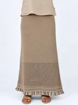 Pollera larga de punto color marrón, con diseño calado en el dobladillo y detalles de volados y costuras en tono rojizo.