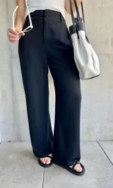 Pantalón negro de lino de corte holgado, con cintura alta y cierre con doble botón.