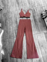 Conjunto de dos piezas compuesto por un top corto tipo bralette con escote en V y un pantalón estilo palazzo de corte oxford, ambos en color rosado con estampado de rayas verticales finas.