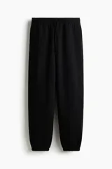 Jogging negro en felpa con interior cepillado, cintura elástica con cordón ajustable, bolsillos laterales y puños elásticos en los tobillos.