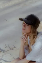 Gorra de béisbol negra de cuero sintético con hebilla metálica ajustable en la parte posterior.