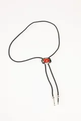 Collar bolo de cordón trenzado negro con dije ovalado de piedra roja engarzada en metal plateado y terminales metálicas plateadas.