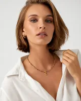 Collar corto confeccionado con cristalitos facetados en tonos marrones y grises, intercalados con pequeñas cuentas doradas y un dije central en forma de luna.