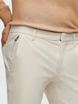 Pantalón de vestir color beige, corte slim fit, con bolsillos laterales y traseros.