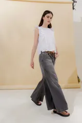 Pantalón de jean color beige, de tiro medio, corte amplio y ruedo acampanado.