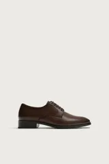 Zapato tipo derby de vestir en color marrón, con diseño de parte superior lisa, horma redonda y suela con ligero tacón.
