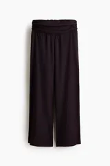 Pantalón de corte holgado en punto arrugado de color negro. Modelo de tiro alto con pretina fruncida de doble capa y piernas amplias.