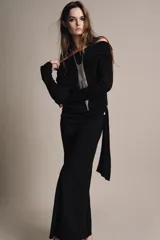 Vestido largo de color marrón oscuro, con cuello fluido tipo bote, manga larga y detalle de fruncido lateral con broche metálico en la cintura.