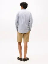 Camisa celeste de algodón regenerativo con textura dobby, cuello camisero clásico, cierre con botones y puños abotonados. Tiene corte regular, manga larga y logo de Tommy Hilfiger bordado en el pecho.