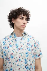 Camisa de manga corta confeccionada en tela 100% algodón con estampado de cachemir en tonos naranja y celeste. Tiene un bolsillo en el pecho y botones personalizados.