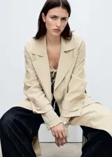 Abrigo largo tipo trench de diseño recto y fluido, con cuello de solapas con muesca, cierre delantero, cinturón tipo batín y mangas largas con trabillas.