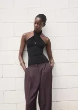 Top negro entallado sin mangas, con cuello halter cruzado.
