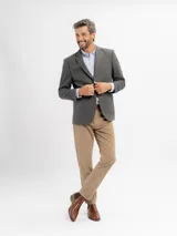 Saco de paño gris de corte regular fit, con cuello de solapa clásica, bolsillos frontales con solapa, bolsillo ojal en el pecho y cierre de dos botones.