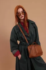 Bandolera de diseño rectangular en color suela, confeccionada en material sintético. Cuenta con un asa superior fija, correa larga ajustable y extraíble, y dos bolsillos frontales con cierre metálico, uno de ellos con diseño superpuesto. Presenta el logo de la marca grabado en el frente.