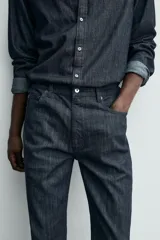 Jeans de corte slim fit en color azul oscuro, con diseño de cinco bolsillos, cierre frontal con cremallera y botón, y tejido ligeramente elástico.