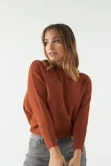 Sweater color ladrillo de punto liviano con textura acanalada y diseño de hombros caídos.