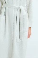 Bata de estar por casa con diseño acolchado, cuello solapa, mangas largas y lazo ajustable en la cintura. Cuenta con bolsillos frontales aplicados.