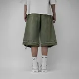 Bermuda baggy de denim 100% algodón en color verde militar, con efecto acid wash, corte ancho, largo hasta la rodilla y detalles deshilachados en el ruedo. Presenta bordado contrastante con el nombre de la marca en la pierna izquierda.