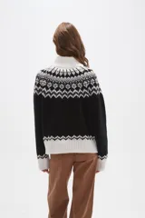 Sweater de punto con diseño jacquard en cuello, puños y ruedo. Presenta cuello alto, mangas largas y corte holgado.