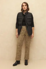 Chaleco puffer color crema, con cuello alto, cierre frontal y cuatro bolsillos con solapa. Cuenta con cintura ajustable con cordón.