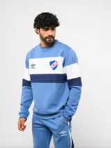 Buzo de cuello redondo confeccionado en felpa, con diseño de bloques de color en azul, rojo y blanco. Presenta el logo de Umbro y el escudo del Club Nacional de Football bordados en el frente.