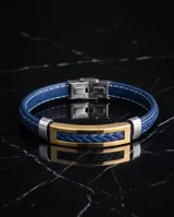 Pulsera masculina con correa de cuerina trenzada en color azul y placa central rectangular con baño de oro y detalles en acero.