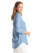Blusa de lyocell color azul con efecto denim, cuello camisero con solapa y escote en V con cierre de un botón. Presenta mangas largas con terminación doblada y ruedo redondeado.