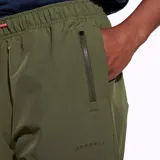 Pantalón jogging color verde oliva confeccionado en nylon reciclado con tecnología DWR (Durable Water Resistance). Cuenta con cintura y puños elásticos, cordón de ajuste naranja, dos bolsillos laterales abiertos y un bolsillo con cierre en la parte superior.