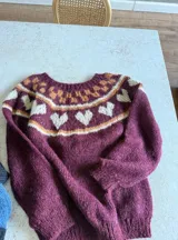Sweater de punto tejido a mano en mohair, con diseño de canesú estampado en tonos azul, rojo, blanco y turquesa. Presenta cuello redondo y mangas largas.