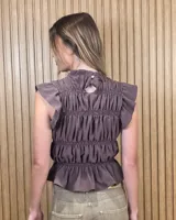 Blusa sin mangas de diseño estructurado con múltiples líneas de frunces y elásticos horizontales, cuello alto con volado y diseño ajustado. Presenta estampado de rayas verticales.