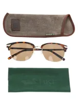 Lentes de sol estilo clubmaster con marco superior de acetato en estampado carey y puente y aros inferiores metálicos en tono dorado. Posee cristales polarizados color marrón con protección UV.