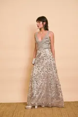 Pollera larga color gris con capa de encaje transparente bordada con lentejuelas plateadas y doradas en patrón floral.