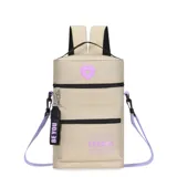 Mochila matera color beige con detalles en lila y negro. Cuenta con un bolsillo frontal extra, correa y llavero desmontable, y tiras con tela mesh. Tiene un parche de corazón lila en la parte superior y la palabra "TRENDY" estampada en lila en el bolsillo frontal.