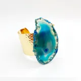 Pulsera dorada tipo brazalete con textura martillada y dije de piedra ágata azul y verde.