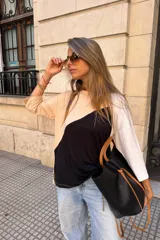 Remerón de manga tres cuartos con diseño tricolor en bloques diagonales: negro en el centro, beige claro en la parte superior izquierda y blanco en la manga derecha.