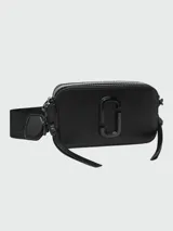Cartera tipo crossbody Marc Jacobs modelo The Snapshot, color negro con acabado monocromático. Presenta el logo metálico frontal, doble compartimento con cierre y correa ajustable de tela.