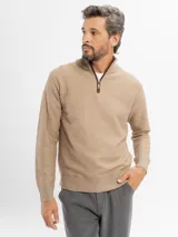 Buzo de tejido de punto color beige con cuello alto y cierre frontal parcial. Presenta puños y ruedo acanalados.