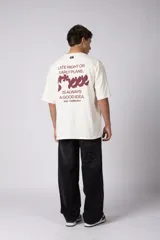 Remera oversize de algodón color beige, de manga corta y cuello redondo, con pequeño estampado frontal de la marca en tono bordó.