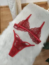 Conjunto de lencería de encaje rojo, compuesto por un bralette de diseño geométrico con tiras elásticas y una tanga con detalles de aberturas laterales.