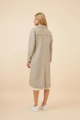 Tapado largo de corte recto confeccionado en lana fina sin teñir. Presenta cuello solapa, cierre frontal con botones, bolsillos laterales con tapa y detalles aplicados en la parte delantera. Incluye forro interior y tajo en la espalda.