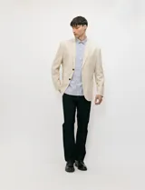 Blazer beige de medio forro confeccionado en mezcla de algodón y lino, con silueta estructurada, solapas de muesca, cierre frontal de dos botones y bolsillos con solapa.