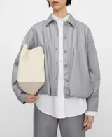 Chaqueta bomber gris con cuello italiano, cierre frontal con broches a presión y bajo abullonado. Las mangas son redondeadas con pinzas en los codos y cuenta con bolsillos verticales en las costuras laterales.