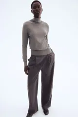 Polera gris de punto fino, con cuello alto, bajo recto y puños acanalados.