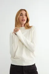 Polera de punto color beige, con cuello alto y mangas largas, de diseño básico y ajuste clásico.