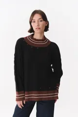 Buzo de tejido de punto con diseño de trenzas, color negro con detalles en marrón y blanco en cuello, puños y ruedo. Presenta un corte oversized con hombros caídos.