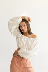 Blusa corta color salmón, con escote recto con elástico, mangas largas abullonadas con elástico en los puños y corte crop.