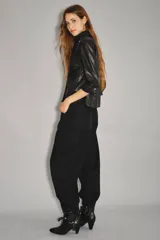 Jean de tiro medio-alto, color negro, de calce holgado con piernas anchas que se estrechan hacia el tobillo. Presenta pinzas en las rodillas que acentúan su forma "balloon" y un recorte lateral. Confeccionado en denim rígido con lavado suavizado, cierre y botón.