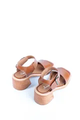 Sandalias de cuero color tostado con tira ancha sobre los dedos, tira al tobillo con hebilla y taco de madera.